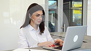 Female customer support operator with headset uses a laptop