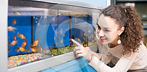 Female customer watching fish in aquarium tank