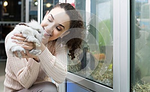 Female customer watching fluffy chinchilla in petshop