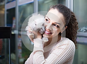 Female customer watching fluffy chinchilla in petshop