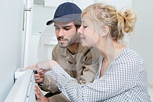 Female customer watching male plumber work