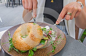 Female cut and eat lunch bagel in restaurant