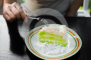 Female cutting pandan coconut cake with fork