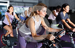 Female cycling on exercise bikes at fitness club