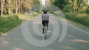 Female cyclist cycling on countryside road. Woman athlete training on bicycle, doing cardio fitness workout exercises. Triathlete