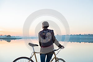 Female cyclist enjoying beautiful blue hour scene by the lake. W