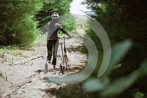 female cyclist guides bicycle as it passes through steep paths