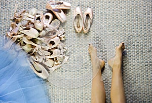 Female dancer feet near a group of used pointe shoes