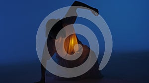 Female dancer performing in the studio. Young woman dancing in dark studio with warm light glowing inside the chest