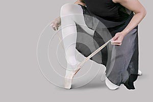 Female dancer ties up her ballet shoes