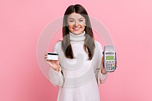 Female with dark hair showing pos payment terminal and credit card, using cashless payments, nfc.