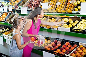 Female with daughter selecting apples in fruit section