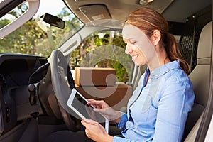 Female Delivery Driver Sitting In Van Using Digital Tablet photo