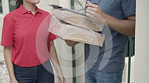 Female delivery worker in red uniform bringing package