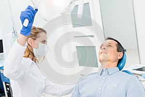 Female dentist adjusting lamp in modern