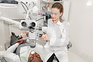 Female dentist advanced user, dental tools. Setup microscope for examining his patients teeth. in dental clinic office