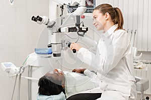 Female dentist advanced user, dental tools. Setup microscope for examining his patients teeth. in dental clinic office