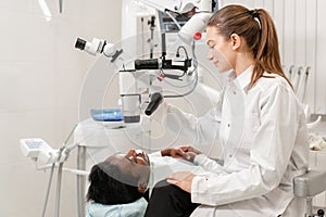 Female dentist advanced user, dental tools. Setup microscope for examining his patients teeth. in dental clinic office