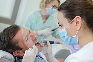 Female dentist with assistant and scared male patient