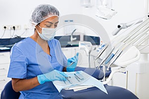 Female dentist checking and arranging tools in dental office