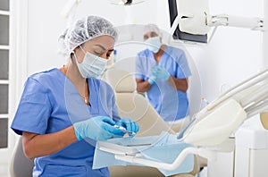 Female dentist checking and arranging tools in dental office