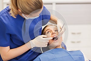 Female dentist checking patient girl teeth