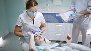 Female dentist checking patient girl teeth. Dentist with mirror checking patient girl teeth up at dental clinic office