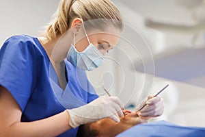 Female dentist checking up male patient teeth