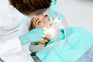 Female dentist checking up patient teeth with braces at dental clinic office. Medicine, dentistry concept. Dental