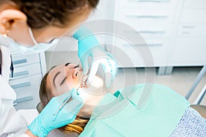 Female dentist checking up patient teeth with braces at dental clinic office. Medicine, dentistry concept. Dental
