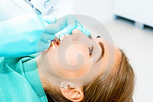 Female dentist checking up patient teeth with braces at dental clinic office. Medicine, dentistry concept. Dental