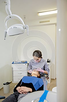 Female dentist checking up patient teeth at dental clinic office. Medicine, dentistry concept. Dental equipment