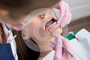 Female dentist checking up patient teeth with metal brackets at dental clinic office. Medicine, dentistry
