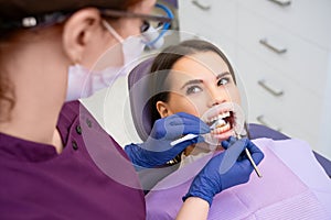 Dentist checks oral cavity of patient with specialized tools photo