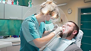 Female dentist checks up teeth of male patient. Steadicam.