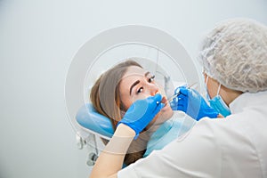 Female dentist curing teeth cavity in blue gloves and protective mask.