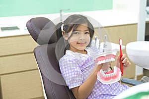 Female dentist demonstrating how to brush teeth to a little girl in dental clinic, teeth check-up and Healthy teeth concept