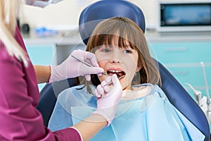 Female dentist in dental office talking with female patient and preparing for treatment. Kids stomatology