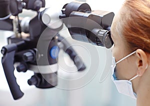 Female dentist with dental tools - microscope, mirror and probe treating patient. Medicine, dentistry and health care