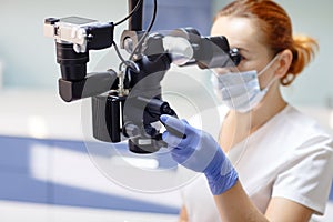 Female dentist with dental tools - microscope, mirror and probe treating patient. Medicine, dentistry and health care