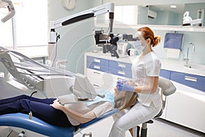 Female dentist with dental tools - microscope, mirror and probe treating patient. Medicine, dentistry and health care