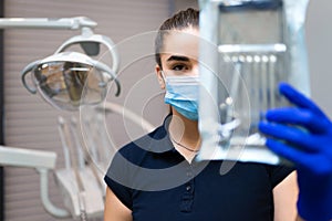 Female dentist doctor holds sterilized instruments.