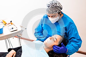 Female dentist doing an maxillofacial exam to a female patient photo