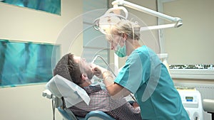 Female dentist drilling tooth of patient in dental clinic. Slider shot, right.