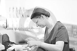 A female dentist examines the oral cavity of a patient