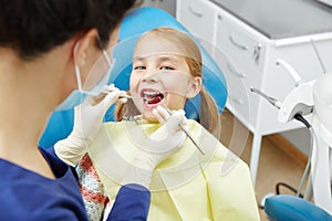 Female dentist examines of smiling child at the pediatric dentistry clinic.