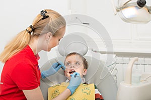 Female dentist examines the teeth of the patient child. Child mouth wide open in the dentist`s chair. Close-up