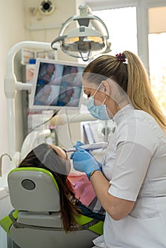 Female dentist examining a female patient teeth with intraoral camera and watch at the screen