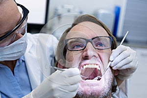 Female dentist examining male patient with tools