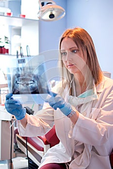 Female dentist examining x-ray image of teeth in dental clinic.